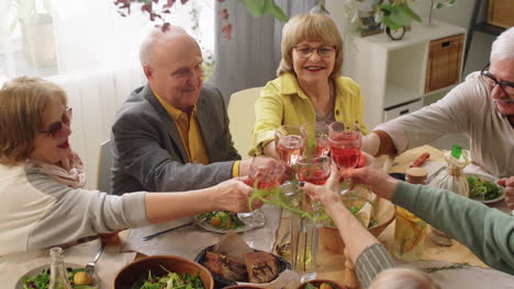 Senior-Friends-Clinking-Drinks-in-Toast-at-Dinner